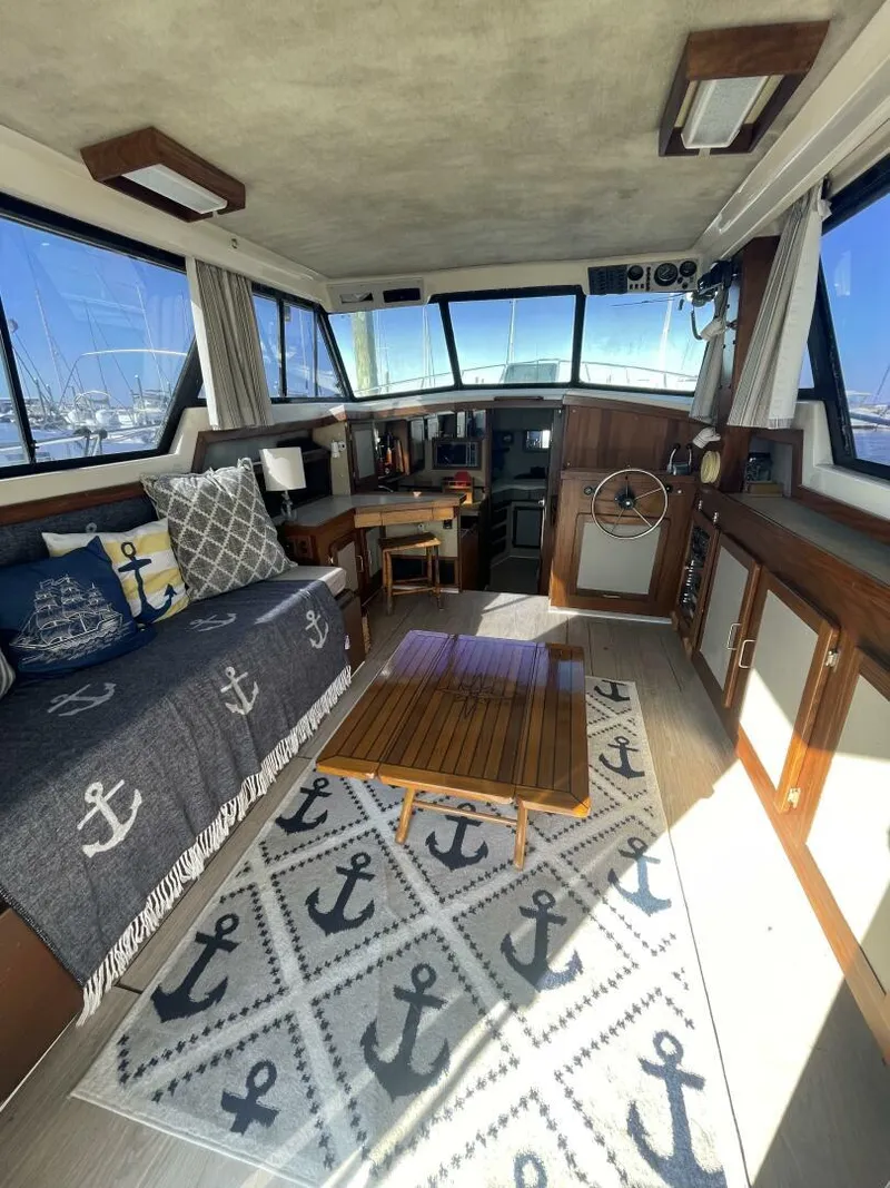 Slide: The Image of 1984 Mainship MK III boat interior with nautical decor, featuring anchor-themed cushions and rug. - 6