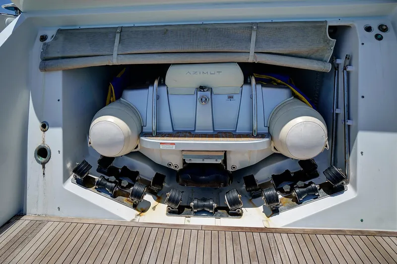 Slide: The Image of 2015 Azimut 55S yacht with tender storage compartment, featuring inflatable boat and rollers. - 24