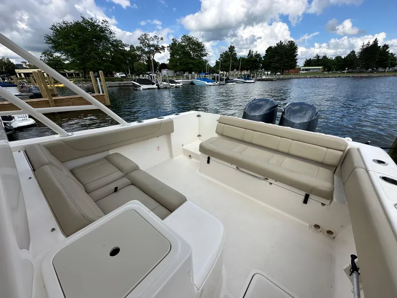 Slide: The Image of 2015 Pursuit ST 310 Sport boat interior with seating, docked by a scenic waterfront. - 19