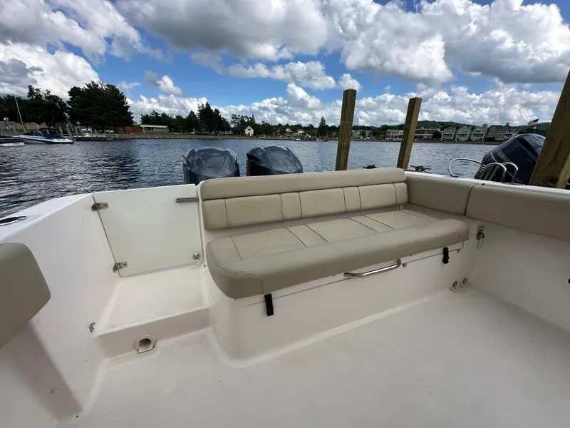 Slide: The Image of 2015 Pursuit ST 310 Sport boat interior with beige seating, docked by a scenic waterfront. - 21