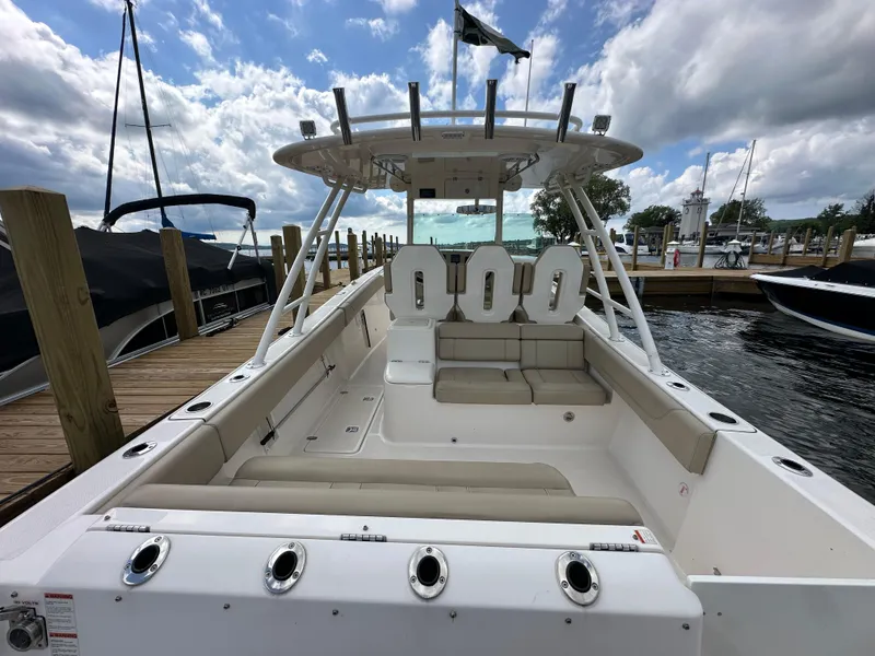 Slide: The Image of 2015 Pursuit ST 310 Sport boat docked, featuring spacious seating and sleek design under a cloudy sky. - 22