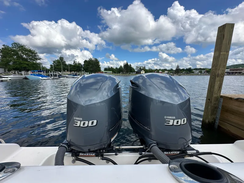 Slide: The Image of Twin Yamaha 300 engines on a 2015 Pursuit ST 310 Sport boat, docked by a scenic lake. - 5