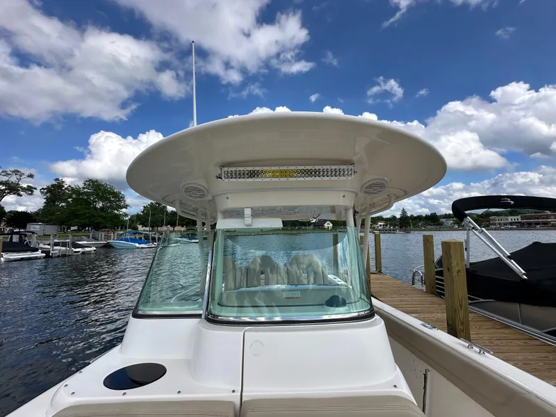 Slide: The Image of 2015 Pursuit ST 310 Sport boat docked under a partly cloudy sky. - 8