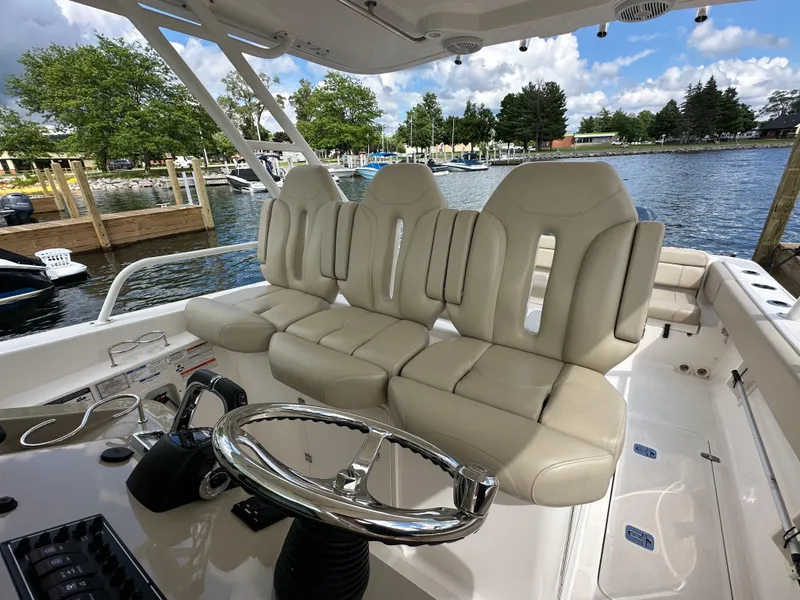 Slide: The Image of Interior of 2015 Pursuit ST 310 Sport boat with beige seating and steering wheel. - 9