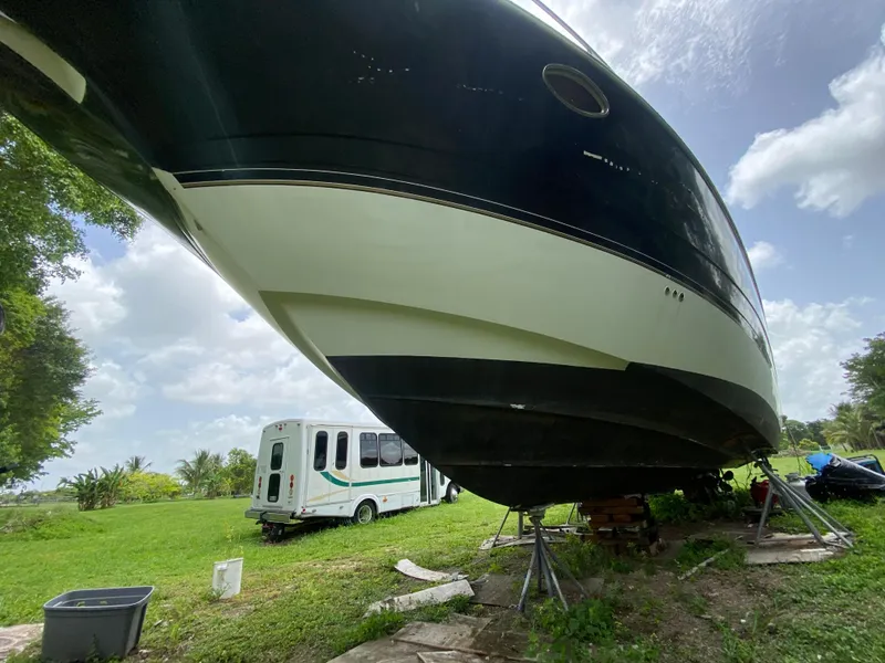 Slide: The Image of 2000 Cruisers Yachts 3870 Express on land, with RV in background, under cloudy sky. - 10