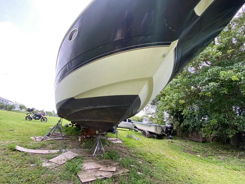 Slide: The Image of 2000 Cruisers Yachts 3870 Express on stands, grassy area, motorcycle nearby. - 12