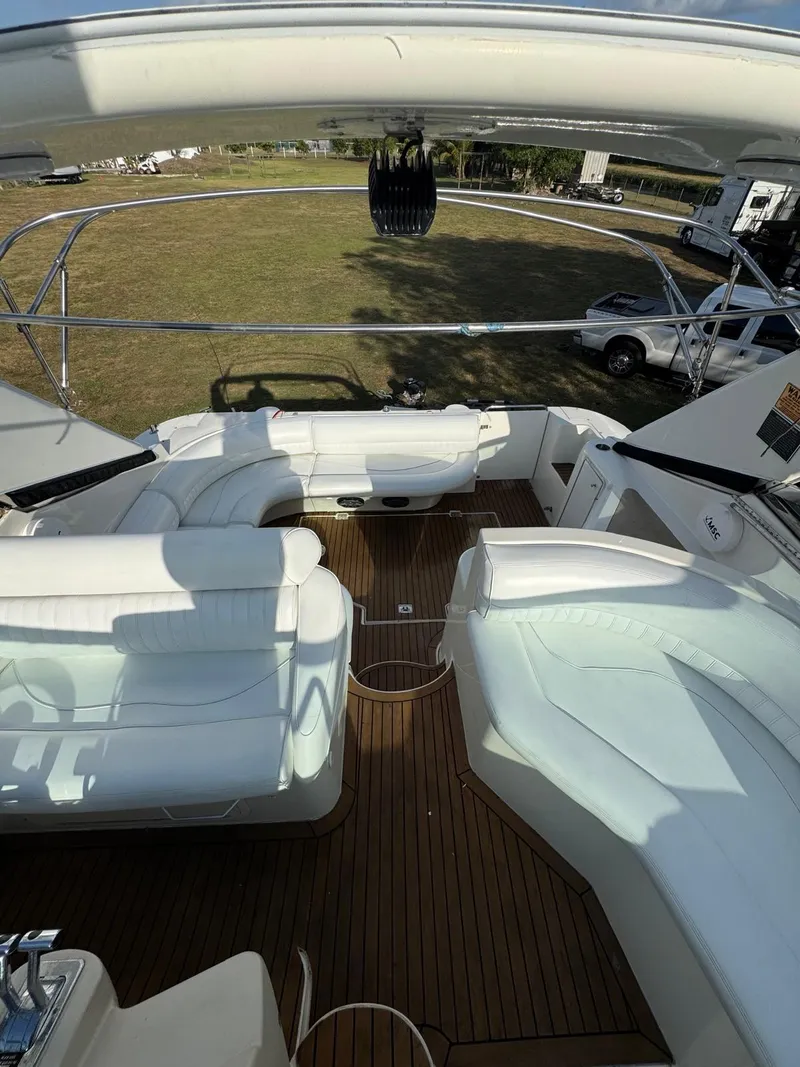 Slide: The Image of 2000 Cruisers Yachts 3870 Express interior with white seating and wooden deck. - 14