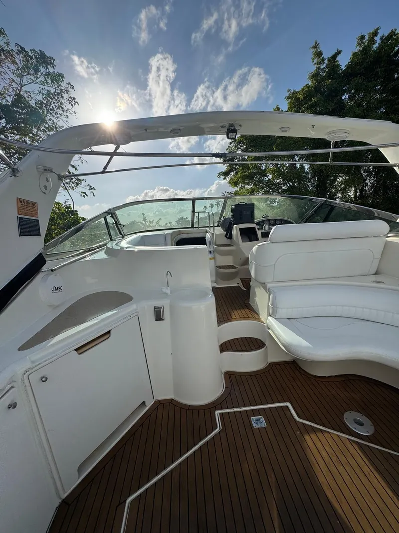 Slide: The Image of 2000 Cruisers Yachts 3870 Express interior with white seating and wooden deck. - 17