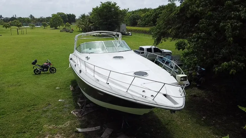 Slide: The Image of 2000 Cruisers Yachts 3870 Express on land, surrounded by greenery and vehicles. - 2