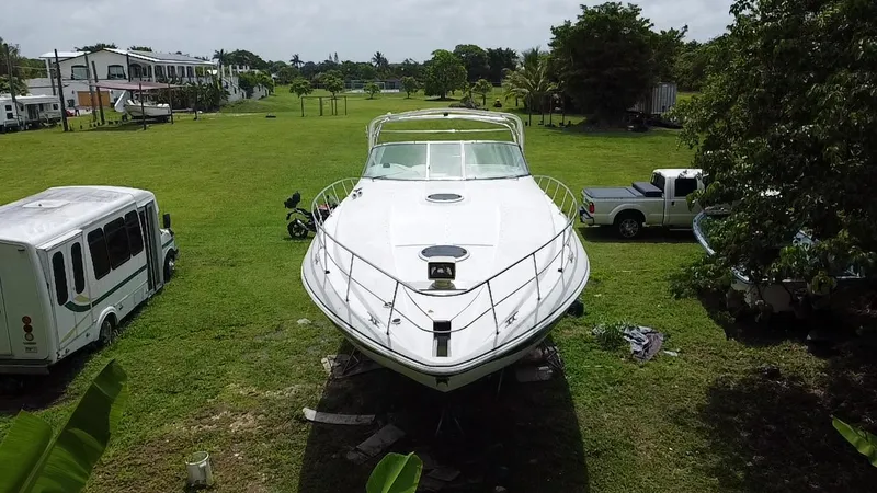 Slide: The Image of 2000 Cruisers Yachts 3870 Express on grass, surrounded by vehicles and trees. - 3