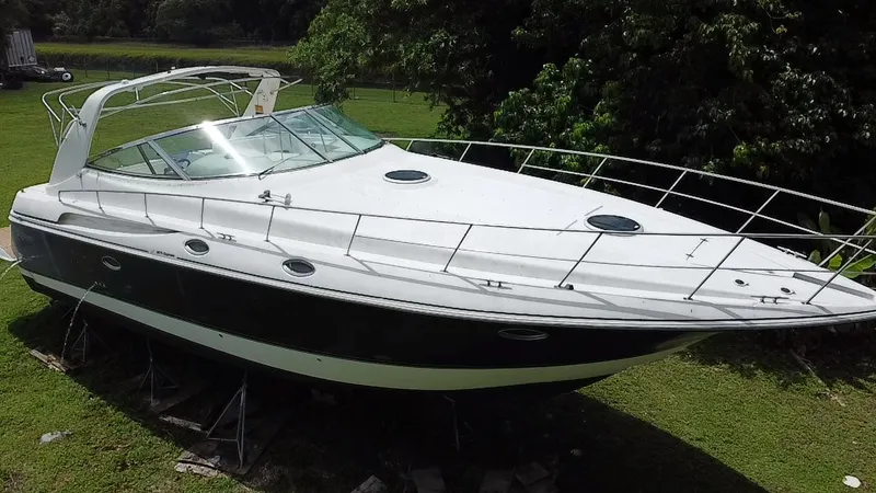 Slide: The Image of 2000 Cruisers Yachts 3870 Express boat on land, surrounded by greenery. - 4