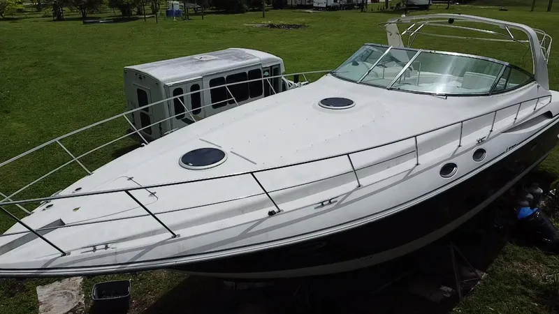 Slide: The Image of 2000 Cruisers Yachts 3870 Express boat on grass, near a white trailer. - 6