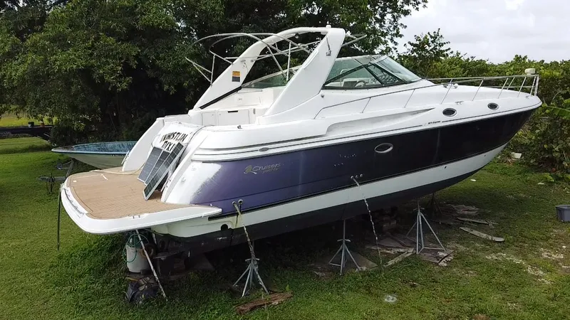 Slide: The Image of 2000 Cruisers Yachts 3870 Express on stands, parked on grass, with lush greenery background. - 7