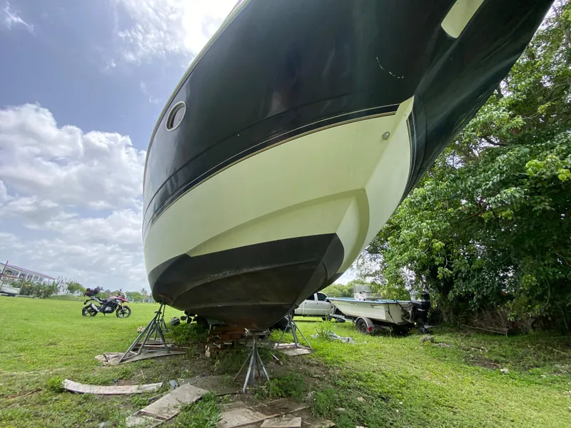 Slide: The Image of 2000 Cruisers Yachts 3870 Express on land, supported by stands, with trees and sky background. - 9