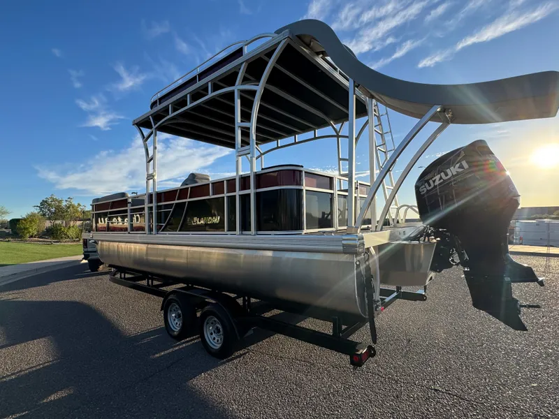 Slide: The Image of 2024 Landau Island Breeze 252 pontoon boat with Suzuki engine, parked on a trailer. - 2