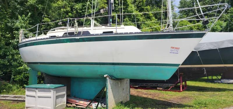 The Image of 1984 Caliber 28 sailboat on land, for sale, with green and white hull. - 1