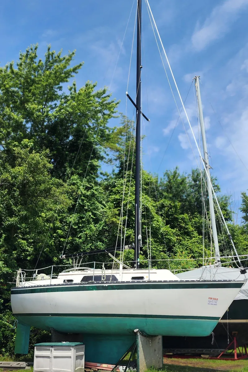 Slide: The Image of 1984 Caliber 28 sailboat on land, surrounded by lush greenery and blue sky. - 23