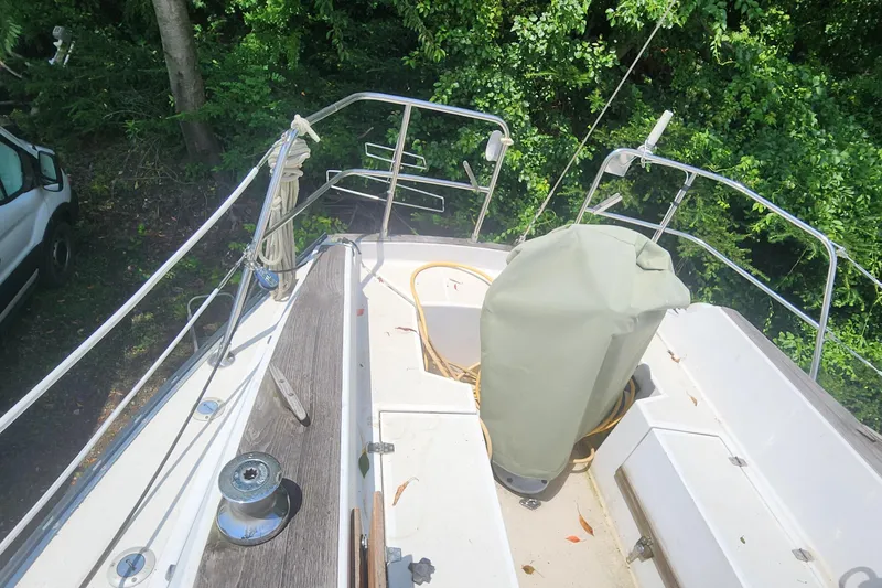 Slide: The Image of Deck view of a 1984 Caliber 28 sailboat surrounded by lush greenery. - 26