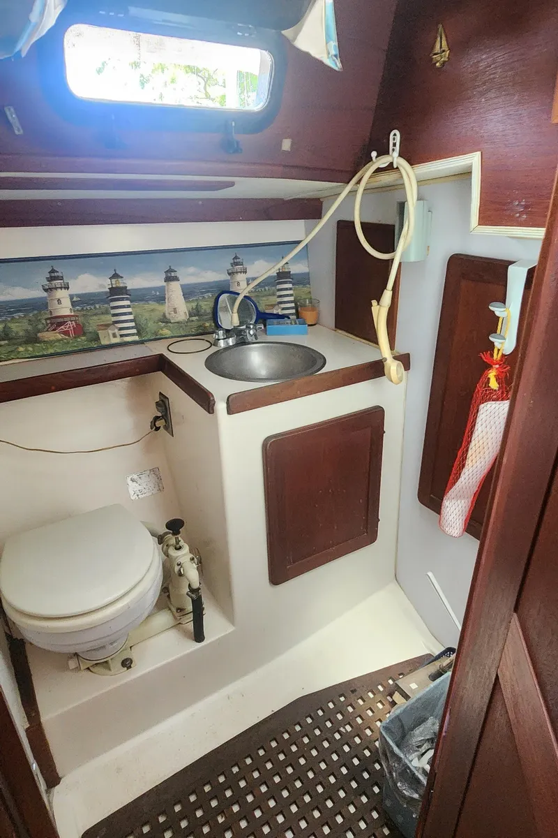 Slide: The Image of 1984 Caliber 28 sailboat bathroom with sink, toilet, and lighthouse-themed decor. - 27