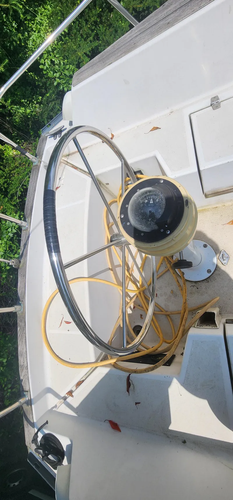 Slide: The Image of 1984 Caliber 28 sailboat cockpit with steering wheel and compass, surrounded by greenery. - 3