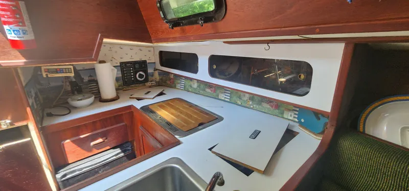 Slide: The Image of Interior of a 1984 Caliber 28 sailboat kitchen with wooden cabinetry and countertop. - 6