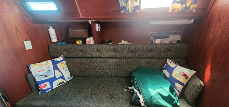 Slide: The Image of Cozy interior of a 1984 Caliber 28 sailboat with cushioned seating and nautical-themed pillows. - 8