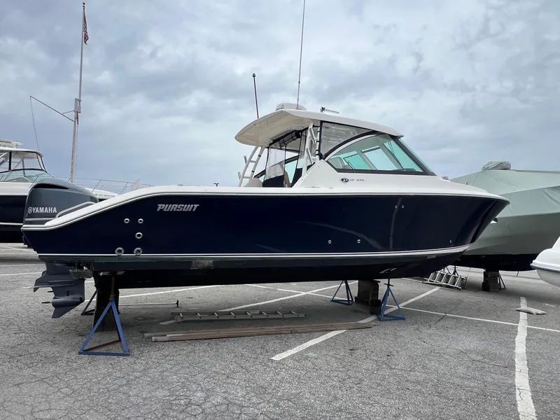 The Image of 2016 Pursuit 325 DC boat on stands in a marina setting. - 0
