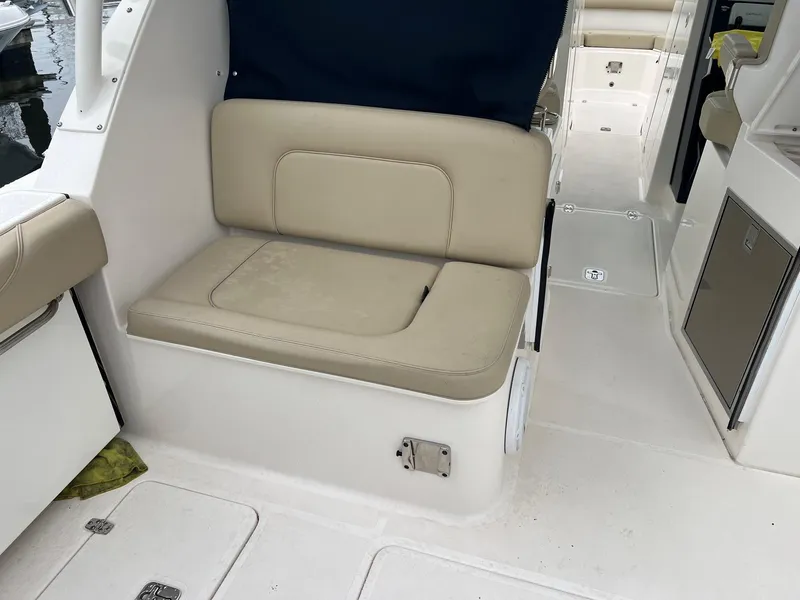Slide: The Image of 2016 Pursuit 325 DC boat interior with beige seating and white flooring. - 10