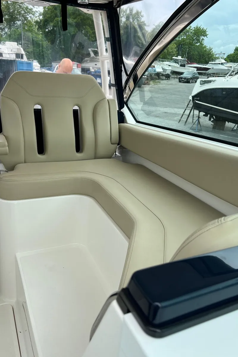 Slide: The Image of Interior seating of a 2016 Pursuit 325 DC boat, featuring beige upholstery. - 14