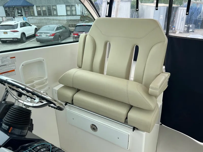 Slide: The Image of Captain's chair on 2016 Pursuit 325 DC boat, featuring beige upholstery and armrests. - 15