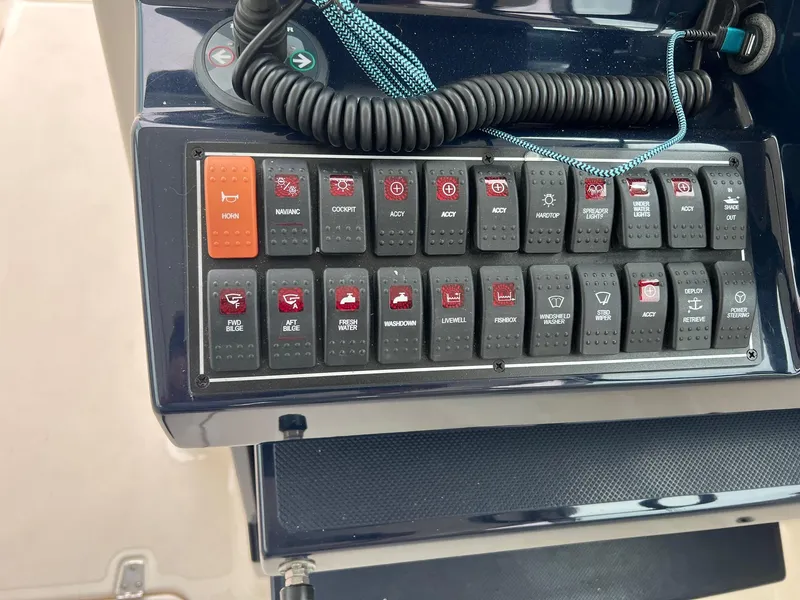 Slide: The Image of Control panel of a 2016 Pursuit 325 DC boat with various switches and buttons. - 21