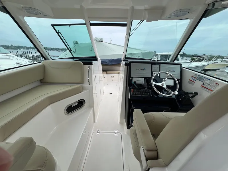 Slide: The Image of 2016 Pursuit 325 DC boat interior with beige seating and Garmin navigation system. - 23
