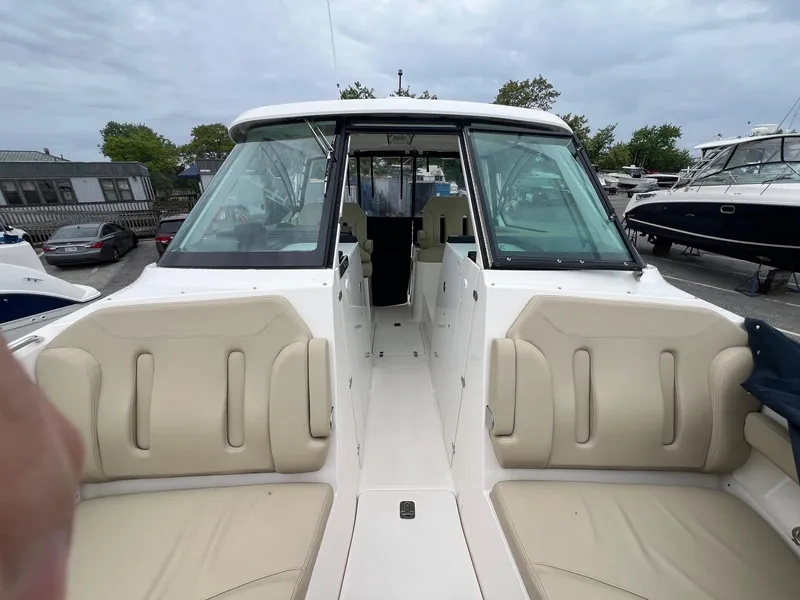 Slide: The Image of 2016 Pursuit 325 DC boat interior with beige seating, docked in a marina. - 27