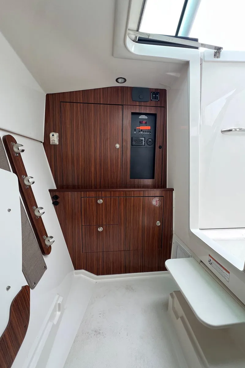Slide: The Image of 2016 Pursuit 325 DC cabin interior with wood paneling and control panel. - 29