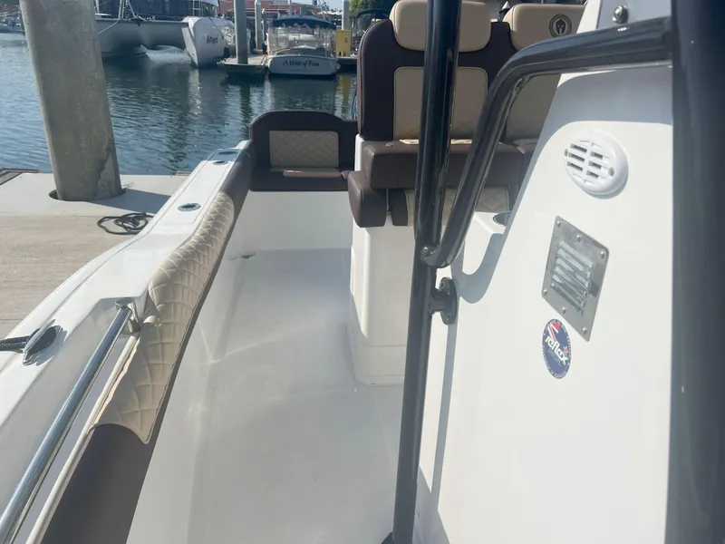 Slide: The Image of 2026 Reflex Gladiator 2400 boat interior at marina, featuring cushioned seating and sleek design. - 21