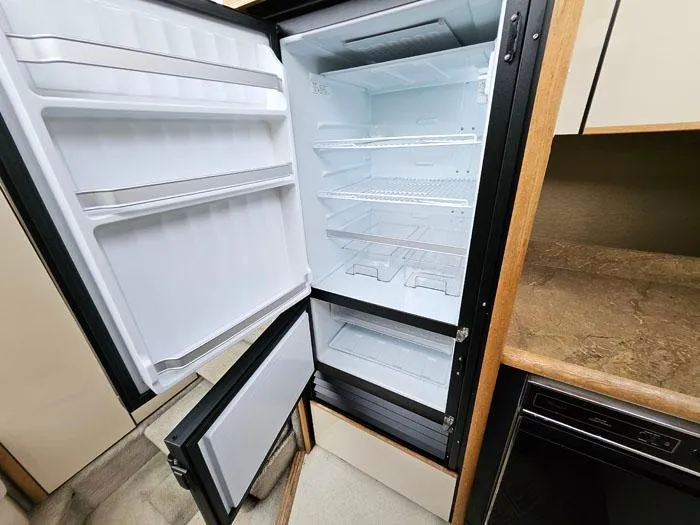 Slide: The Image of Open refrigerator inside 1990 Bayliner 4387 Motoryacht, showcasing spacious interior and shelving. - 18