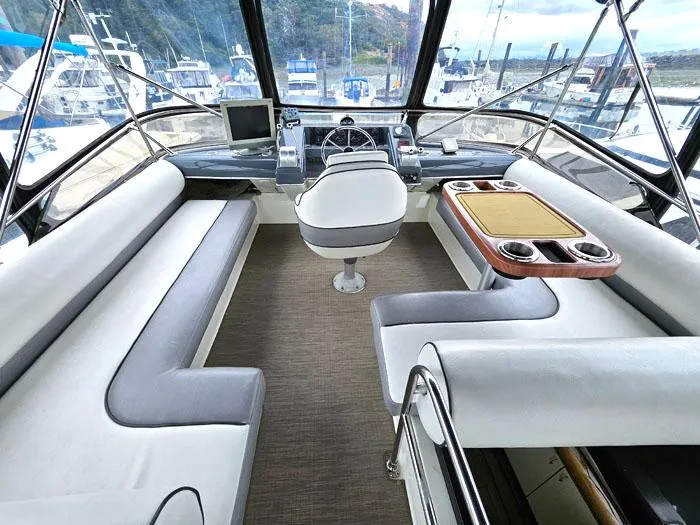 Slide: The Image of 1990 Bayliner 4387 Motoryacht helm with seating, steering wheel, and navigation equipment. - 4