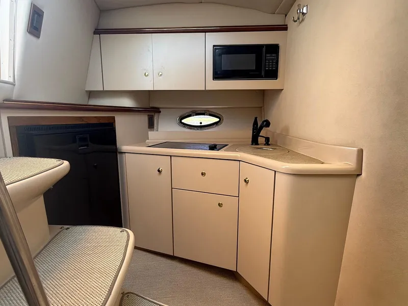 Slide: The Image of 2000 Cruisers Yachts 3375 Express interior kitchen with microwave, sink, and cabinets. - 16