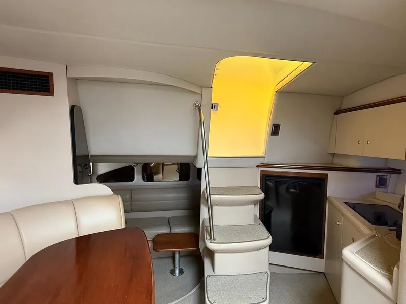 Slide: The Image of Interior of 2000 Cruisers Yachts 3375 Express, featuring seating, kitchenette, and stairs. - 24