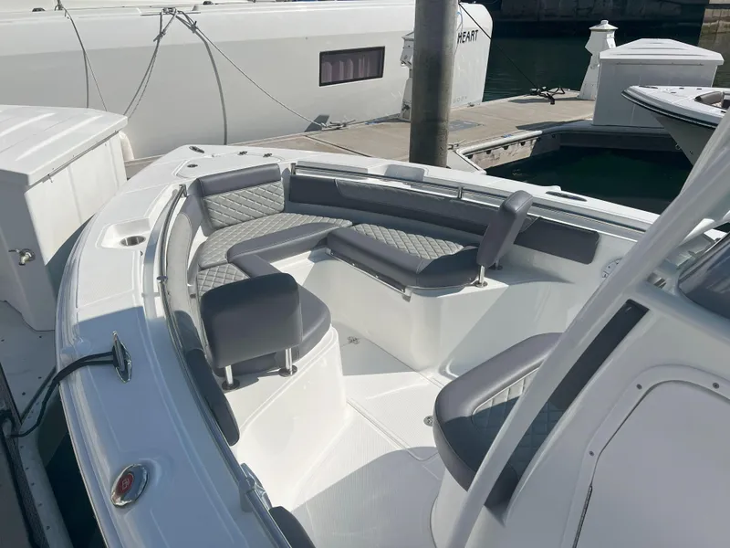 Slide: The Image of 2026 Reflex Gladiator 2400 boat interior with cushioned seating at a marina. - 14