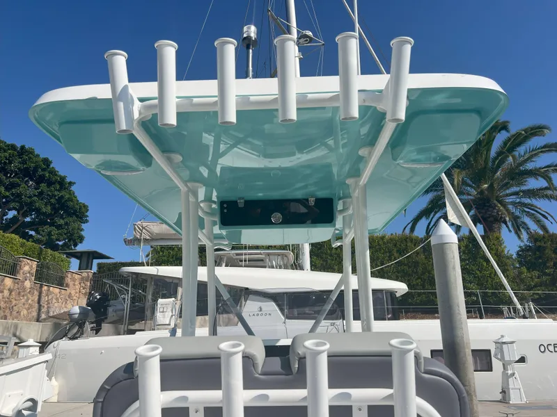 Slide: The Image of 2026 Reflex Gladiator 2400 boat with rod holders, docked under clear blue sky. - 25