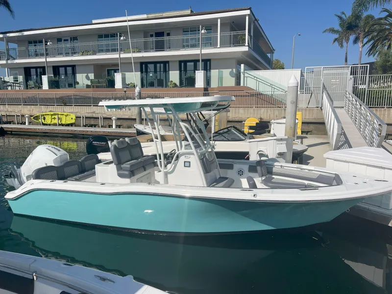 Slide: The Image of 2026 Reflex Gladiator 2400 boat docked at marina, modern design, turquoise hull, sunny day. - 3