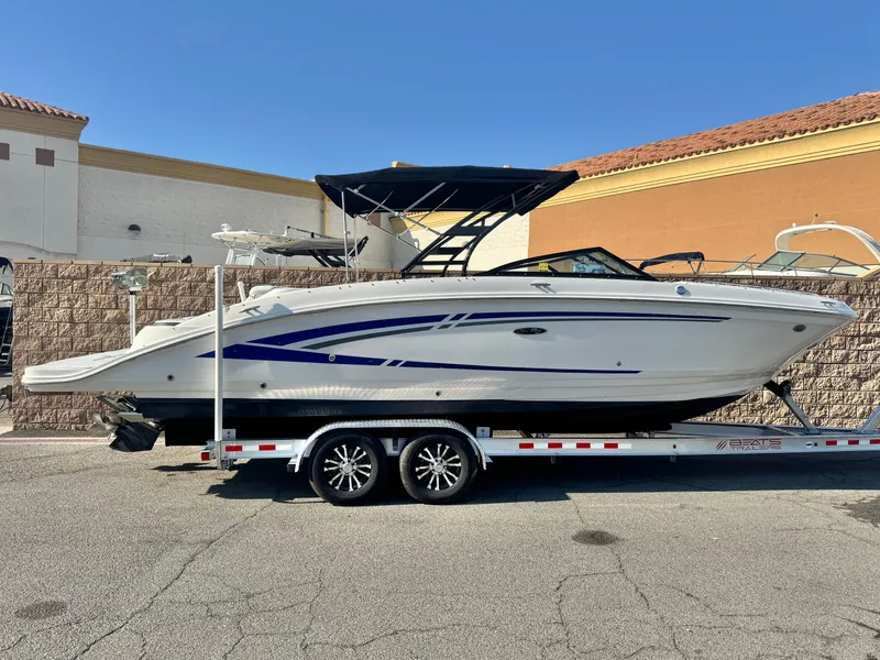 The Image of 2015 Sea Ray 270 SDX boat on trailer, parked outdoors under clear blue sky. - 0