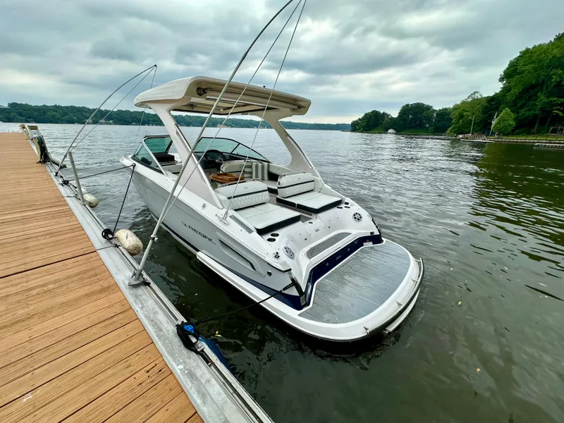 Slide: The Image of 2023 Regal 2800 Bowrider docked on a serene lake under cloudy skies. - 1