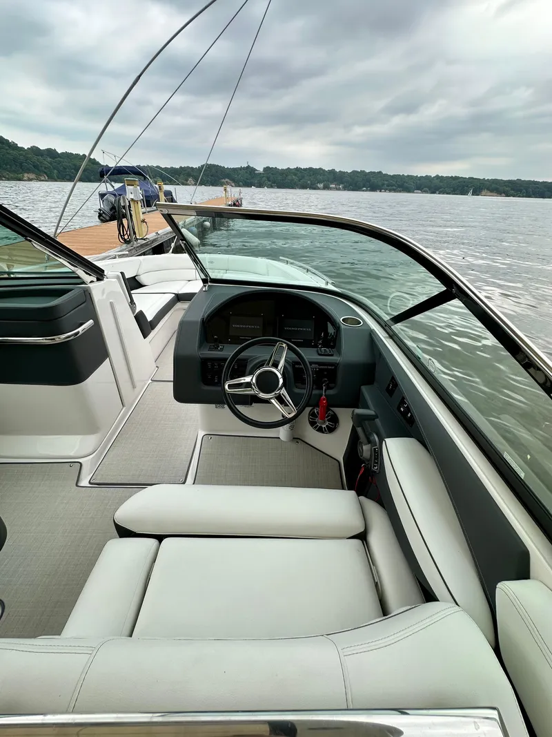 Slide: The Image of 2023 Regal 2800 Bowrider interior with steering wheel, docked on a calm lake. - 12