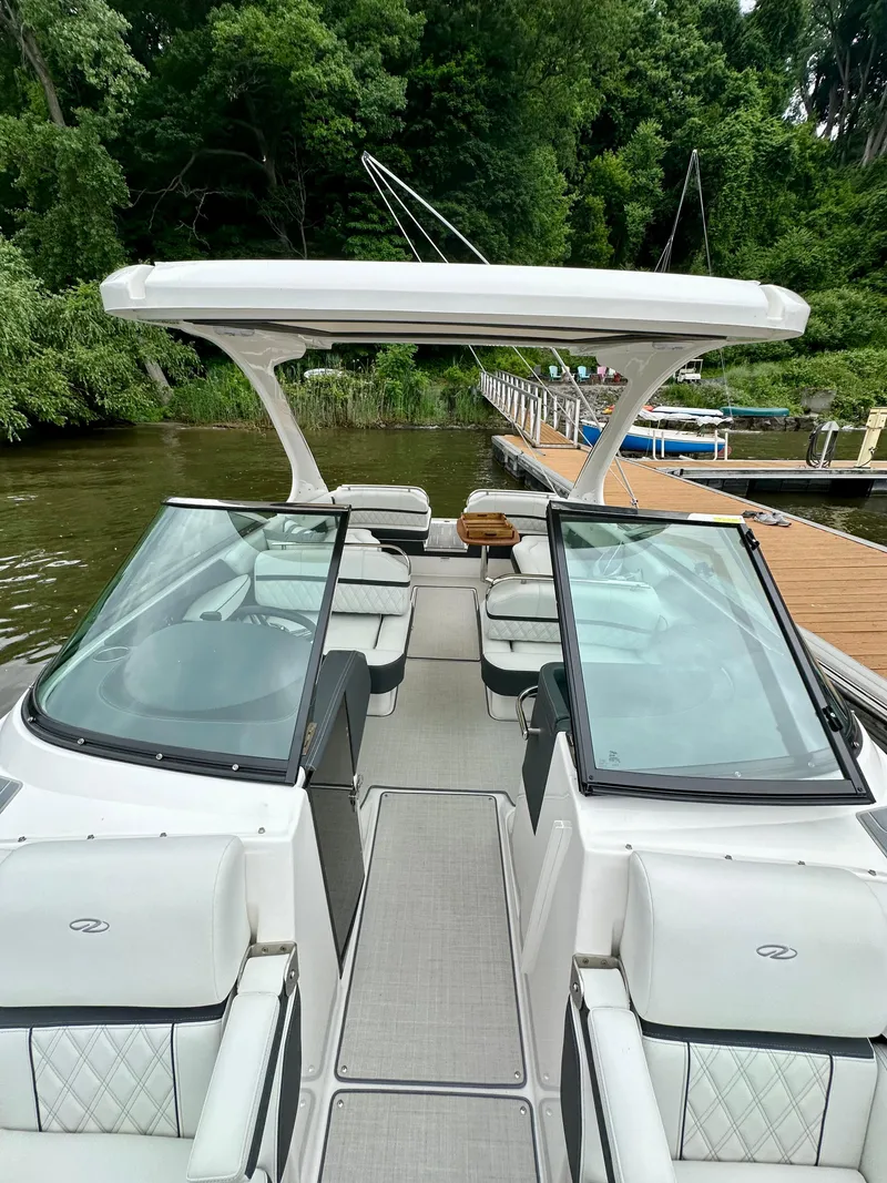 Slide: The Image of 2023 Regal 2800 Bowrider boat docked by a lush, green shoreline. - 16