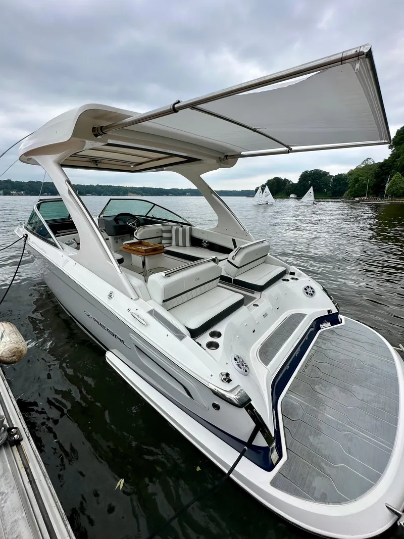 Slide: The Image of 2023 Regal 2800 Bowrider boat with canopy on a lake, surrounded by sailboats. - 2