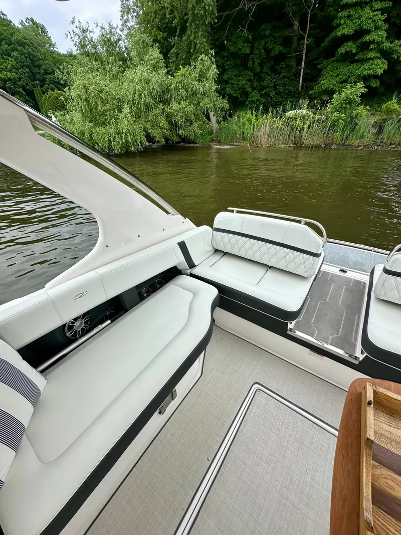 Slide: The Image of 2023 Regal 2800 Bowrider interior with white seating, near lush greenery and water. - 7