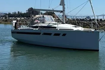 Slide: The Image of 2021 Jeanneau Sun Odyssey 349 sailboat on calm water, with a scenic background. - 3
