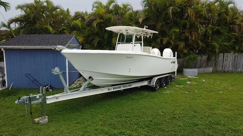Slide: The Image of 2011 Mako 284 CC boat on trailer, parked on grass near blue shed. - 0